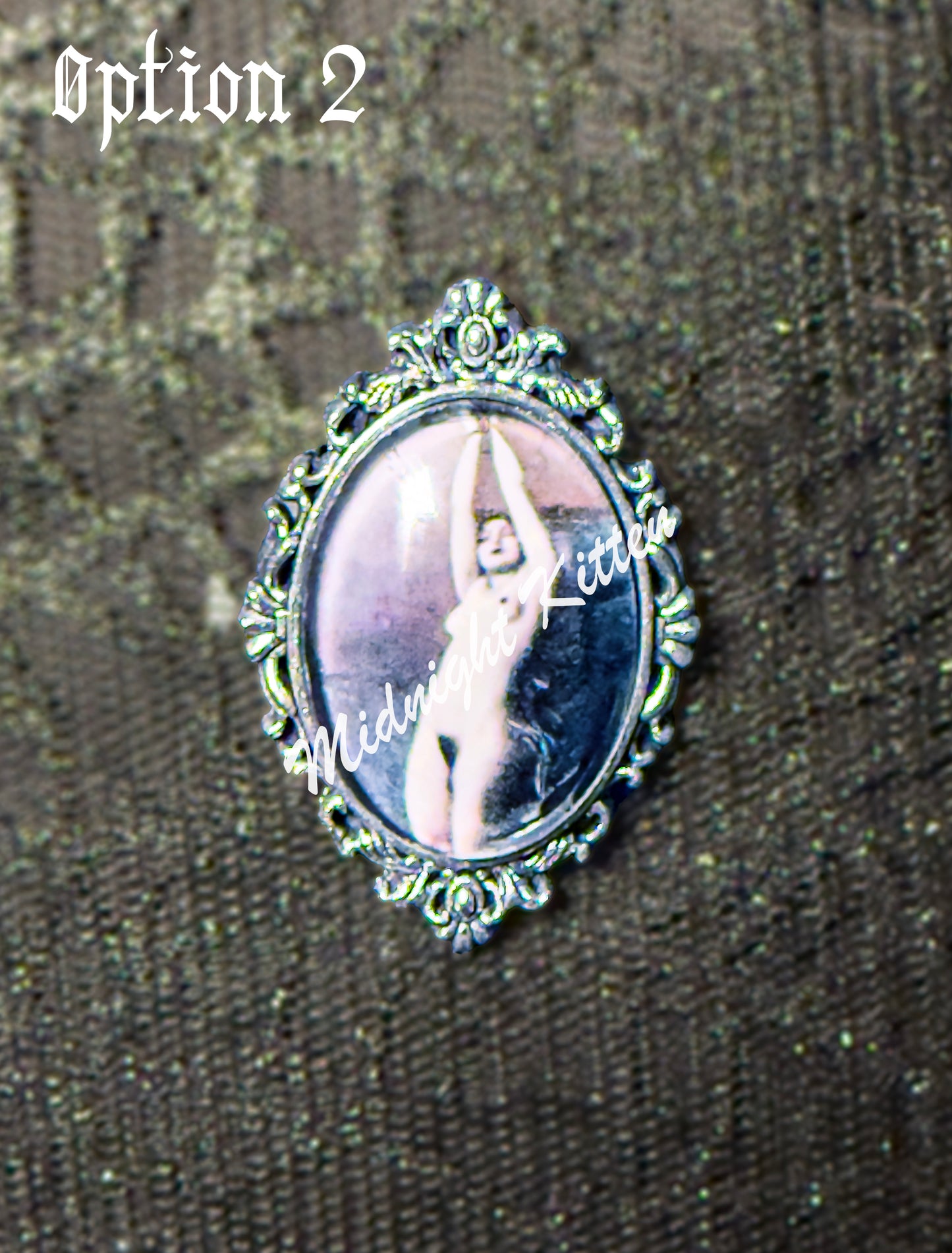 A silver ring with the decorative setting of a framed photograph on a hand against a textured black background. Option 2 contains a Victorian or Edwardian image of a woman bound by her hands which are tied above her head.