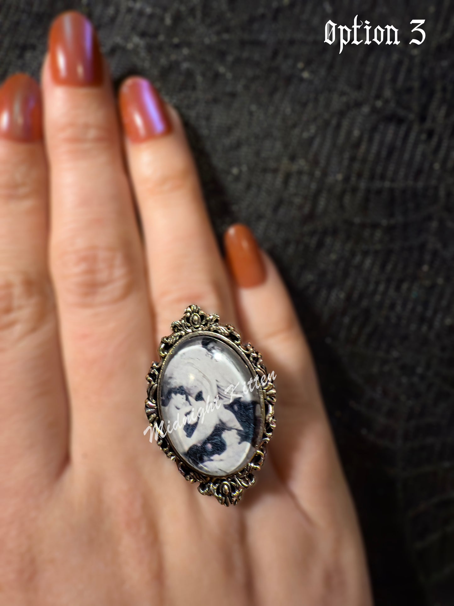 A silver ring with the decorative setting of a framed photograph on a hand against a textured black background. Option 3 contains a Victorian era pornographic image of a ménage à trois.